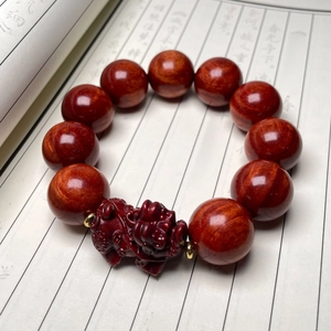 Dettaglio di bracciale in legno di sandalo rosso con ciondolo PiXiu e calligrafia