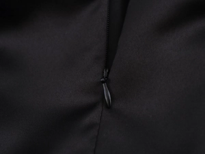 Close-up detail of smooth black fabric texture and hidden zipper on the mini skirt