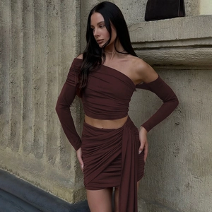 Detail of burgundy two-piece set featuring off-shoulder sleeve and draped pleated mini skirt