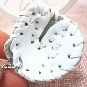 Close-up of a mini white leather baseball glove keychain with woven detailing and ring