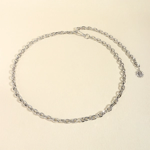 Close-up of silver metal chain belt with a sun and moon pendant on beige background