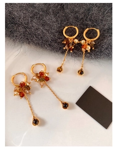 Detail of vintage gold earrings with tiger eye beads, pearls and long chain tassels