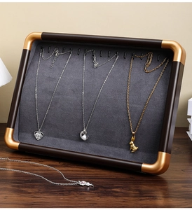 Detailed side view of a walnut wood jewelry display rack with grey velvet and gold corners