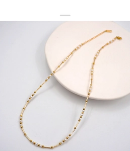 Detailed shot of French vintage pearl and gold bead necklace on a minimalist white tray