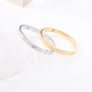 Detailed close-up of gold and silver couple bracelets with engraved baby footprint patterns