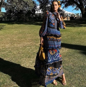 Detail of floral printed maxi dress with stand collar and long sleeves on grass