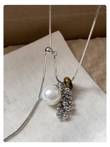 Close-up of pearl cluster necklace with tiger eye stone and silver snake chain