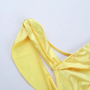 Macro shot of yellow satin fabric texture and stitching detail on the one-shoulder dress