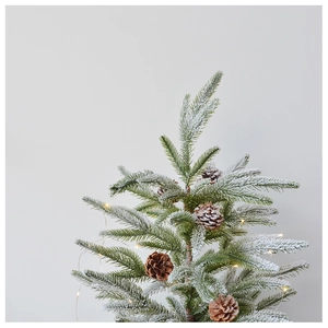 Detail of frosted PE pine needles with natural pine cones and warm LED lights on a snowy tree
