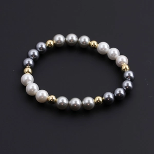Classic beaded bracelet featuring white grey pearls and gold copper beads on black background