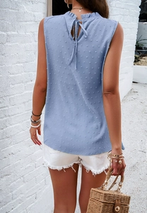 Detail of blue sleeveless top with polka dot texture and back tie-up design on white background