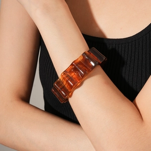 Close-up of translucent amber resin bangle with rippled texture on a model's wrist