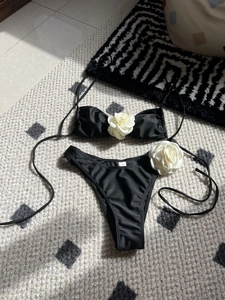 Detail of black bikini set featuring 3D white rose accents and drawstring side straps