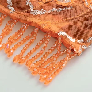 Detail of orange mesh fabric with silver sequins and long beaded fringe tassels