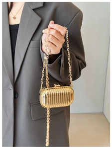 Close-up of mini gold metallic evening bag with vertical stripes and elegant top clasp