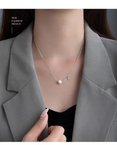 Detailed view of S925 silver necklace featuring a white pearl and letter X pendant