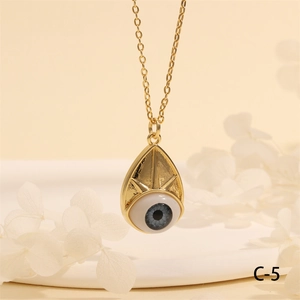Close-up of golden Evil Eye pendant on warm beige background with white petals
