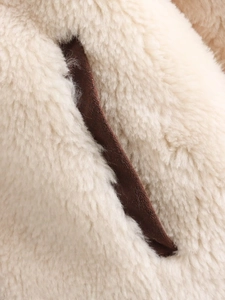 Detailed close-up of cream fleece fabric texture with dark brown suede piping trim