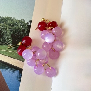 Vue macro des boucles d'oreilles raisin en résine rouge et violette sur un livre