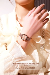 Detailed view of rose gold square watch with Milanese mesh strap on model wrist
