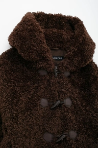Close-up of deep brown faux fur coat showing texture and leather toggle button detail