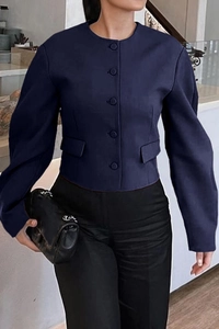 Detail view of navy blue cropped jacket featuring puff sleeves and button-up front closure
