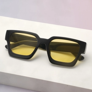 Side view of square thick frame sunglasses with yellow lenses on a white display stand