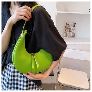 Side view of a grass green crescent underarm bag with polished leather and gold hardware