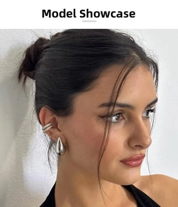 Close-up of woman wearing large silver teardrop earrings and gold-silver ear cuffs