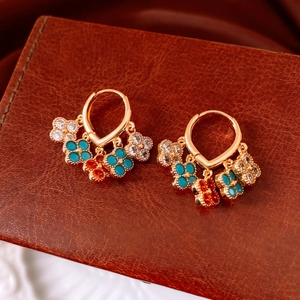 Detail of 18K gold-plated vintage clover earrings with green and orange charms on leather