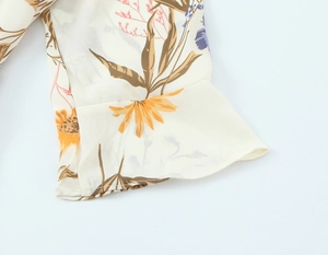 Macro shot of ruffle cuff detail on white floral chiffon dress with yellow and purple print