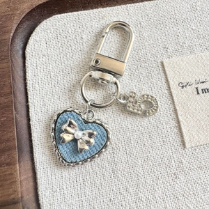 Denim heart keychain with silver bow and pearl detail on a natural wooden tray