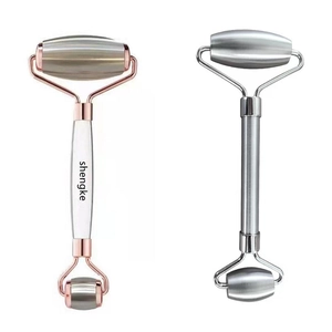 Dual-headed stainless steel face massage rollers in silver and rose gold finishes