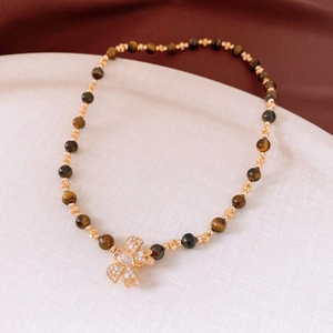 Détail du collier de perles en œil de tigre plaqué or 18 carats avec pendentif nœud