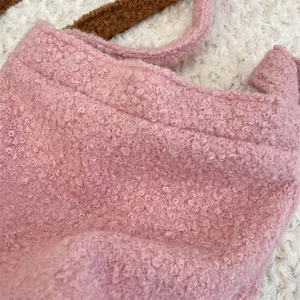 Détail de la texture en laine d'agneau rose et peluche douce sur ce sac à bandoulière