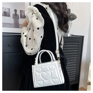 Détail du sac à bandoulière blanc avec motif à cœurs gaufrés et sangle ajustable
