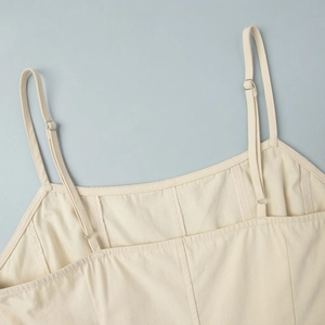 Detail of adjustable thin shoulder straps with metal buckles on a beige cotton dress