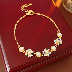 Macro detail of gold flower bracelet with pearls and colored stones on a wooden box