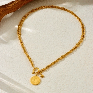 Vintage gold layered necklace with coin portrait and star pendants on beige background