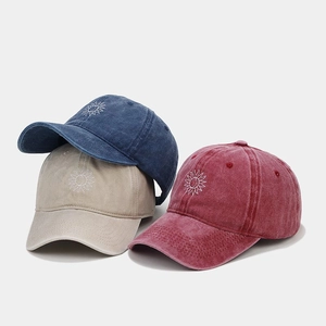Detailed view of washed cotton baseball caps with vintage embroidery in blue, beige, and red
