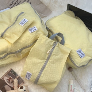 Close-up of yellow waterproof travel organizer bags with grid texture on a plush rug