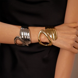 Detailed view of asymmetric open cuff bracelets in polished gold and silver finishes