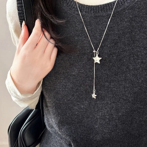 Detailed view of a silver star pendant Y-necklace with adjustable slide on a grey knit sweater