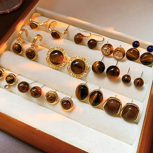 Collection of golden tiger eye stone earrings displayed in a velvet lined wooden box