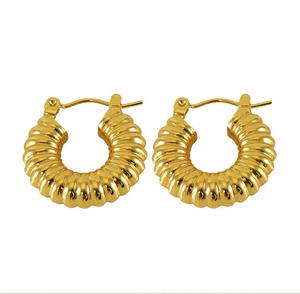 Close-up of golden croissant spiral hoop earrings with classic 18k gold plated texture