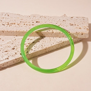 Détail macro d'un bracelet en résine acrylique vert émeraude sur socle en pierre