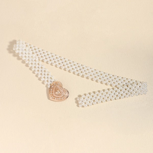Detail of multi-row pearl waist chain featuring a hollow metal heart-shaped buckle