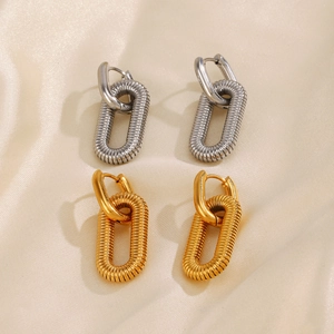 Polished 18K gold and silver oval hoop earrings on elegant silk background
