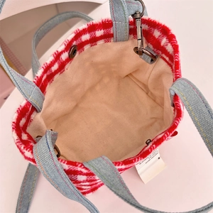 Detail view of red plaid wool tote with denim handles and metal snap closure