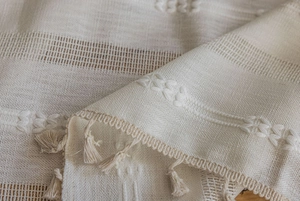 Macro detail of beige striped embroidered curtain fabric with elegant fringe tassels